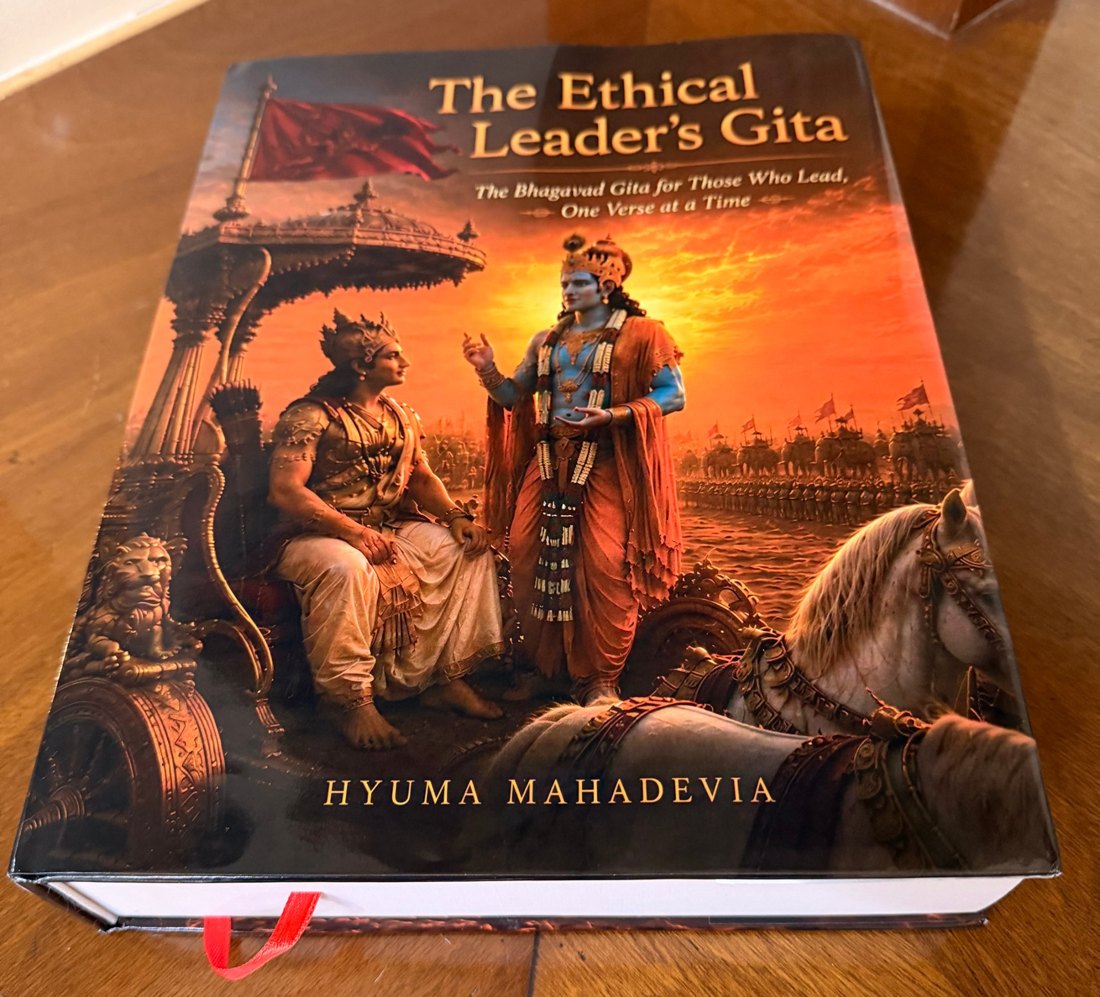 The printed hardback of The Ethical Leader’s Gita lying on a wooden table, front cover up, showing the thickness of its 880 pages and its red ribbon bookmark